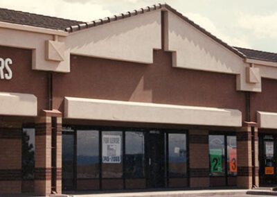 Exterior of a vacant commercial building with a storefront, featuring large glass windows and a sign marked "offers.